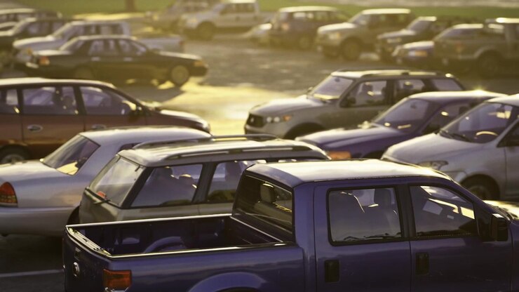 Camionetas y sedanes bañados por el sol dispuestos densamente en un activo distrito comercial.