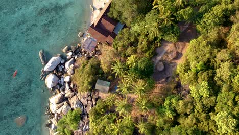 Aerial-reveal-of-kayak-along-rocky-shoreline-at-Freedom-Beach,-Koh-Tao,-Thailand