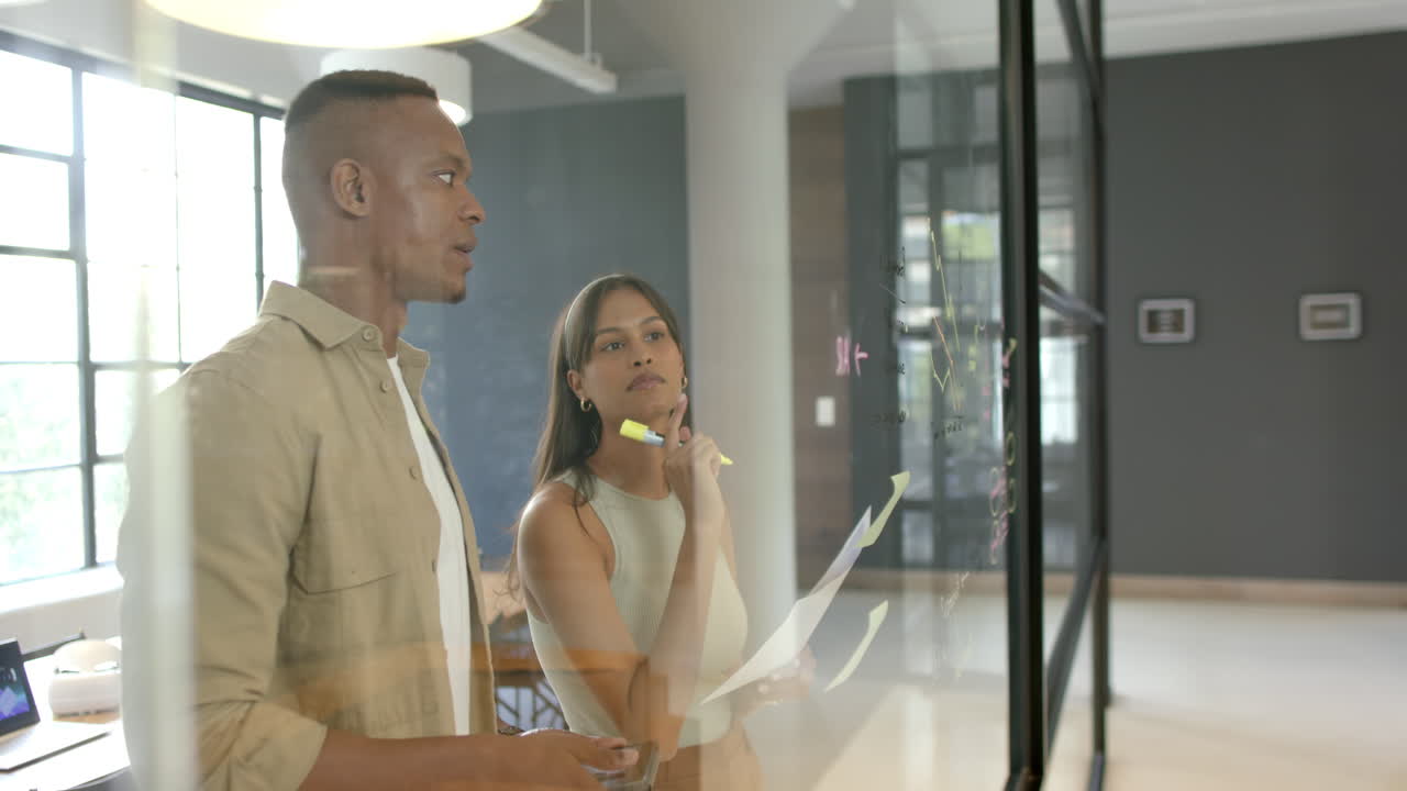 Brainstorming and writing on glass board, business colleagues discussing project in office