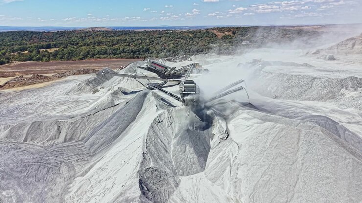 Quarry activity shows machinery working and material being processed during the day in a large open area