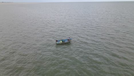 4K-Luftdrohnenaufnahmen-Eines-Fischers-In-Einem-Holzboot,-Der-In-Thailand-Ein-Netz-Von-Oben-Einzieht