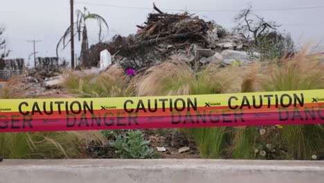 gimbal close-up panning shot of caution tape surrounding fire debris after the palisades fire in southern california. 4k