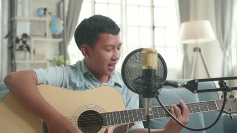 teenager singing and playing guitar at home