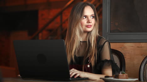 Happy-young-woman-drinking-coffee-and-using-tablet-computer-in-cafe