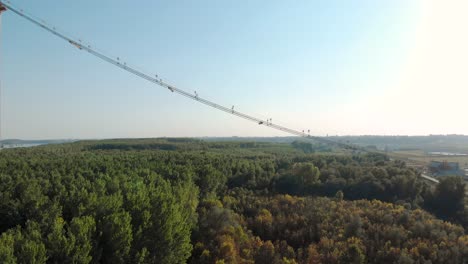 main cable of braila bridge crossing over the vast green forest in romania