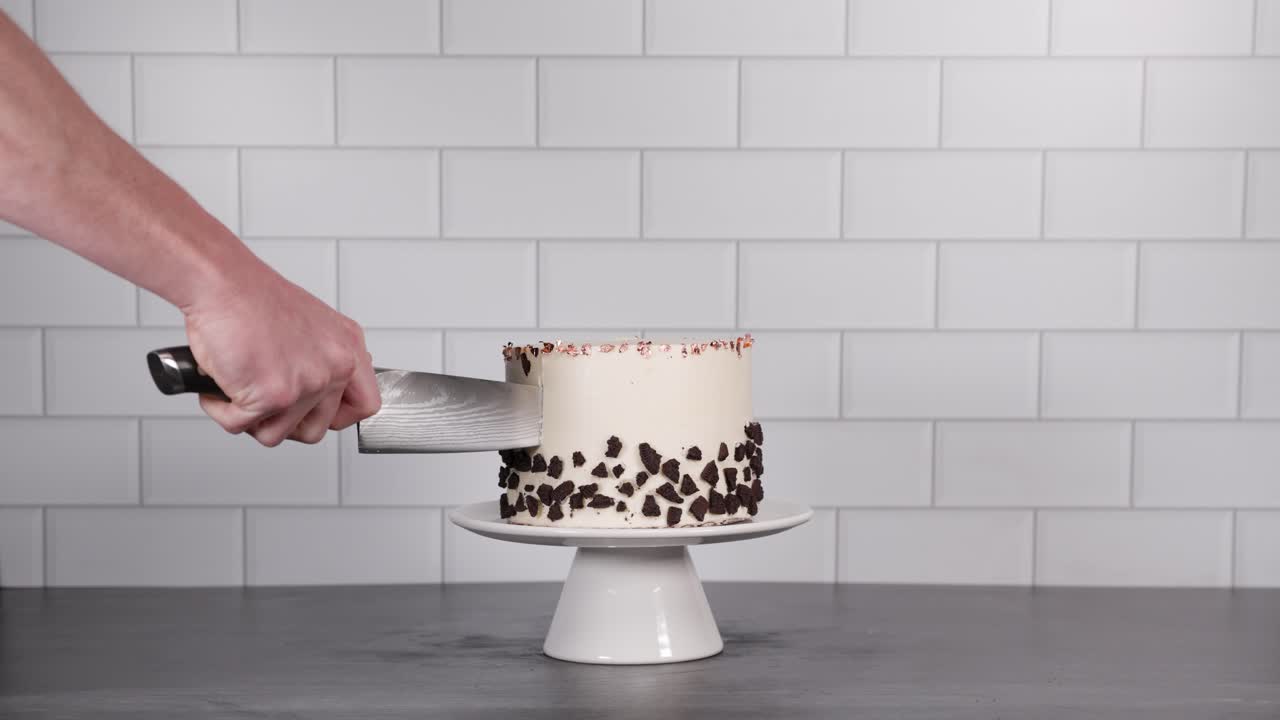 Close-up of a knife slicing through a rich cookie cake topped with gold foil accents, perfect for dessert, baking, or culinary visuals