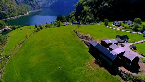 Paisaje-Verde-En-Un-Pueblo-Tranquilo-Con-Un-Lago-Tranquilo-Y-Montañas-Al-Fondo