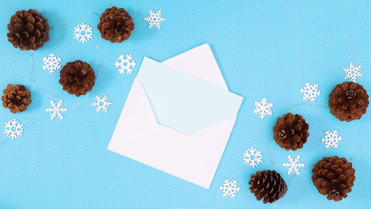 papel en sobre para deseos y luces parpadeantes con conos de pino y copos de nieve. detener el movimiento