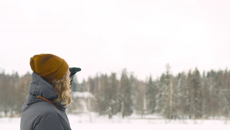 man in winter clothes looking around with a hand in his face in winter forest