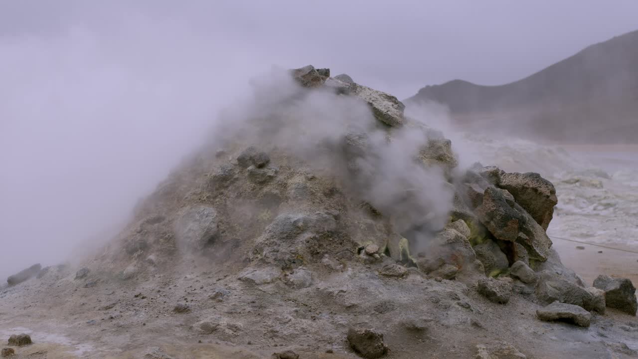 Steam rising from a rugged geothermal hot spring in Namaskaro, Iceland, on a misty day