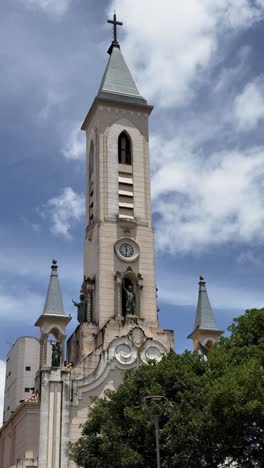 vertical footage of the Viçosa church tower featuring a clock against a blue sky with soft clouds. Capturing the historic architecture and a serene atmosphere, perfect for cultural and scenic visuals