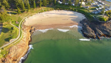 waves on sandy shore of horseshoe bay beach during golden hour - point briner peninsula at south west rocks on mid north coast of nsw, australia