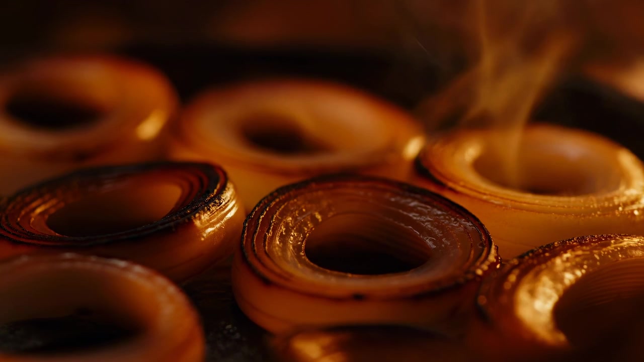 Una vista ravvicinata cattura forme arrotondate stratificate con bordi luminosi, ricche tonalità marroni e una morbida foschia atmosferica che si muove su uno sfondo scuro, creando una texture astratta calma e profondità.