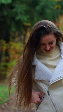 pretty lady walking by in autumn street. attractive young woman walking down the park. vertical video