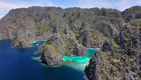 aerial view of twin lagoon in coron, philippines, highlighting jagged limestone cliffs, lush greenery, turquoise waters, and moored boats in a secluded tropical paradise surrounded by deep blue sea