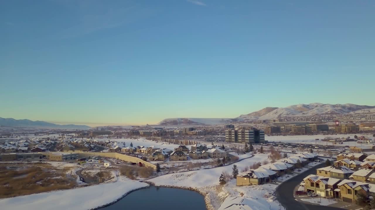 vista aérea de un barrio suburbano con un estanque y algunos edificios de oficinas con montañas al fondo