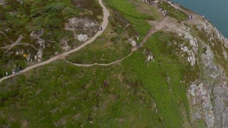 Flying-over-panning-down-cliff-with-tourists-walking-and-trekking-on-the-path