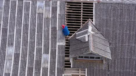 worker repairing roof with sealant near mansard, aerial downwards view