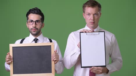 two young multi-ethnic businessmen working together against green background