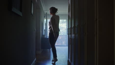 happy beautiful woman wearing headphones dances through her apartment hallway. cheerful authentic girl listening music at home dancing in a good mood. full shot