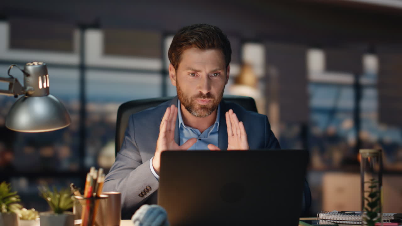 gerente nervioso peleando llamada de portátil hablando en la noche habitación de la oficina de primer plano