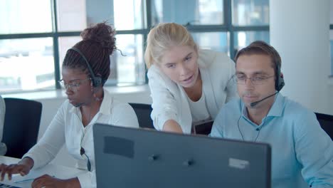 young female boss of call center operators helping her team