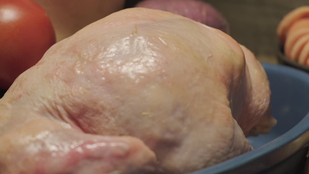 Primo piano statico: pollo crudo in una ciotola blu.