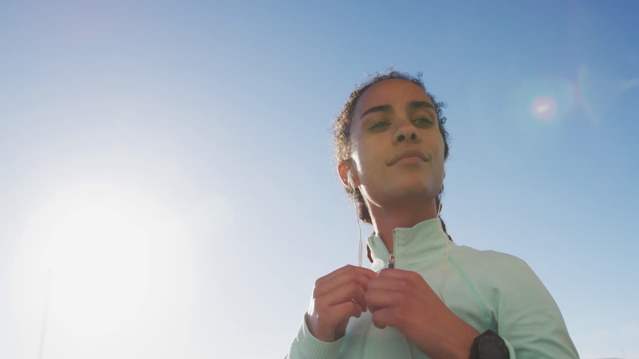 mujer afroamericana en ropa deportiva con auriculares en un día soleado