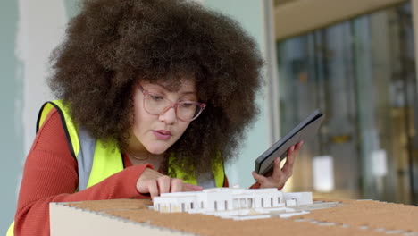 Casual-biracial-female-architect-with-tablet-looking-at-3d-model-in-office,-slow-motion,-copy-space