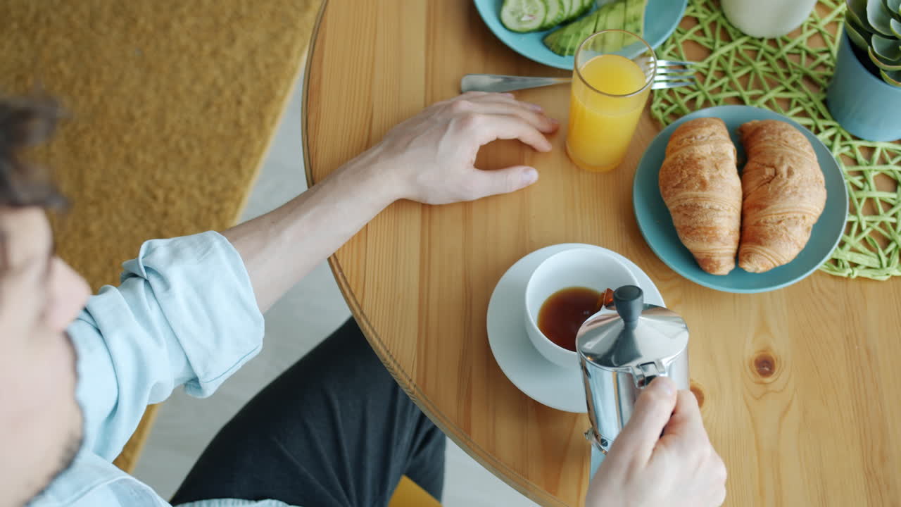 Man having breakfast with coffee and croissant