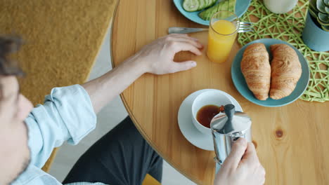man having breakfast with coffee and croissant