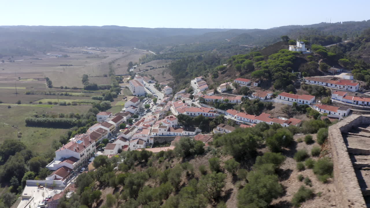 Volo di drone verso le colline con vista su alcune ville ad Aljezur, Algarve, Portogallo.