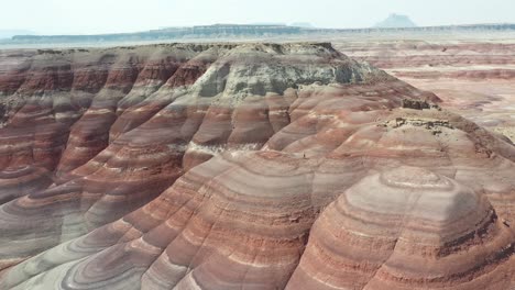 aerial view of scenic layered sandstone hills and lonely man in dry utah desert landscape on hot sunny day, drone shot