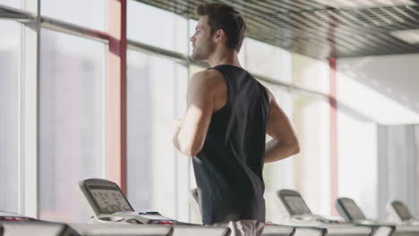Cheerful-man-running-on-treadmill-machine-while-cardio-training-in-gym-club.