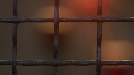 closeup squared iron netting outdoors. defocused bokeh taillights flowing.