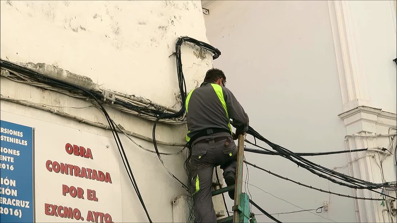 Alora, Spain - November 6, 2018: Men stringing electric cables above busy village street for Christmas lights