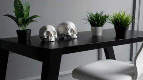white skull sculptures and potted plants on a black table