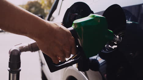 Backlit-close-up-of-Latino-man-pumping-gas-into-Toyota-Prius-at-Gas-Station-on-a-sunny-day