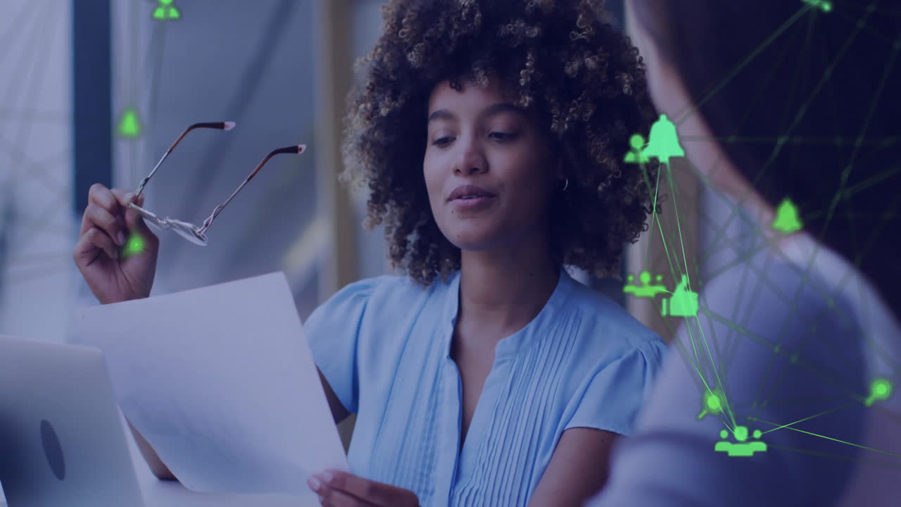 Animation of network of connections with icons over diverse colleagues discussing work in office