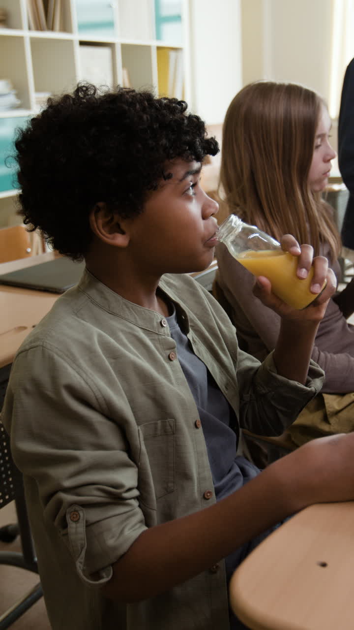 Student drinking juice from a bottle in a classroom