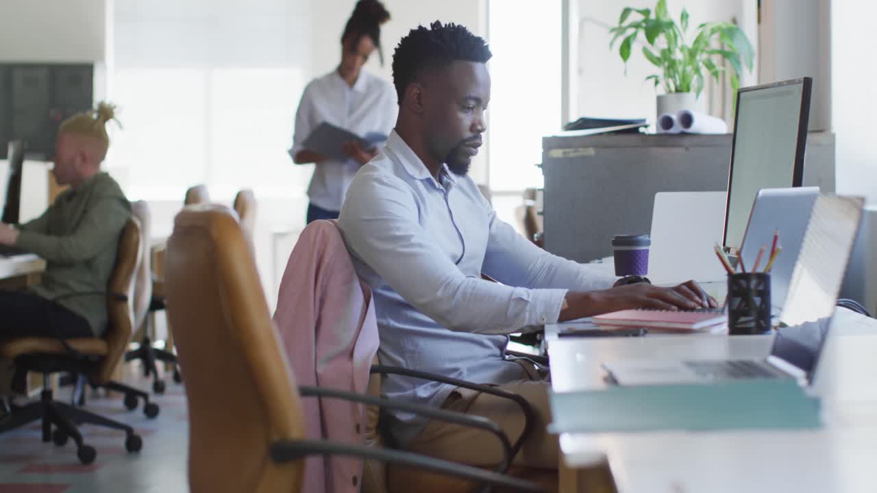 Uomo d'affari afroamericano che usa il laptop con i colleghi in un ufficio creativo