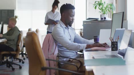 African-american-businessman-using-laptop-with-colleagues-in-creative-office