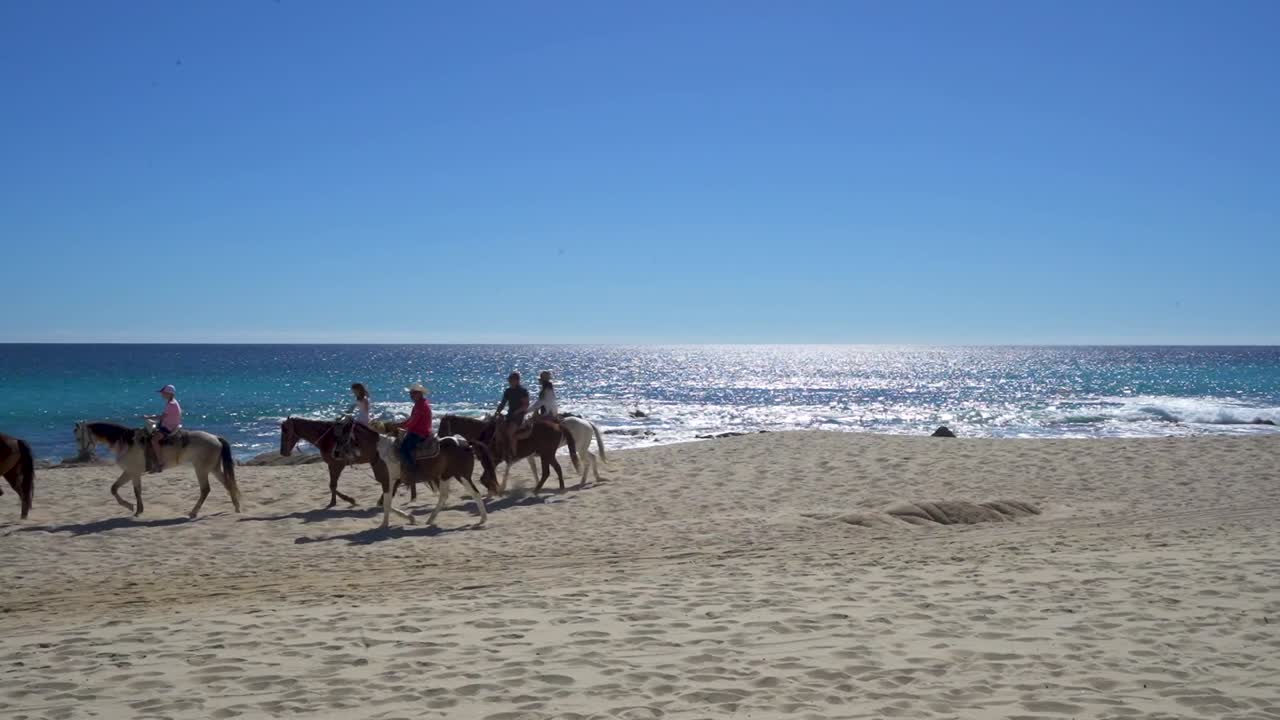 seis pessoas andando a cavalo na praia meio dia, ensolarado, com céu azul