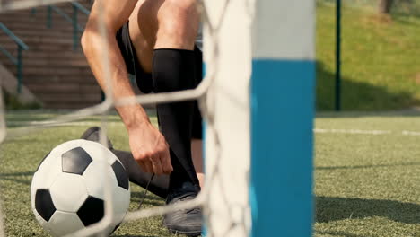 close up of an unrecognizable football player tying his soccer shoes on a street football pitch 1