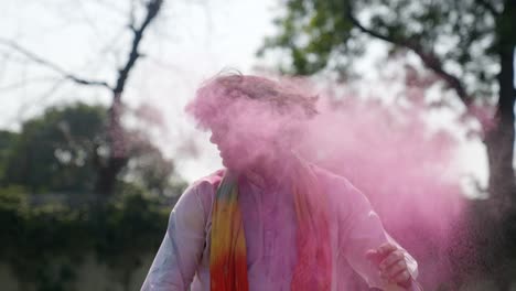 indian man with holi colors in hair, shaking his head