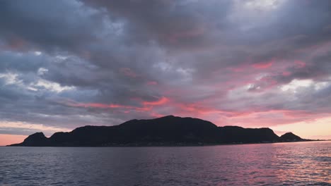 Colorful-sunset-sky-with-dark-stormy-clouds-above-island-silhouette,-static-view