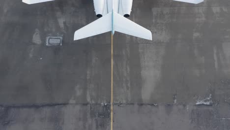 detrás de un gran avión privado estacionado en un aeropuerto de hormigón, revelar tiro