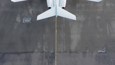 behind large private airplane parked on concrete airport, reveal shot