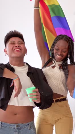 two diverse individuals celebrating with a rainbow flag and cups