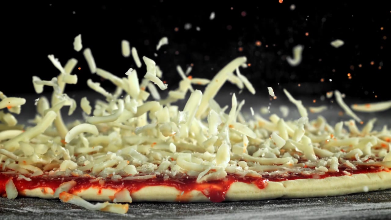 Slow Motion of Shredded Cheese Falling onto Unbaked Pizza Dough